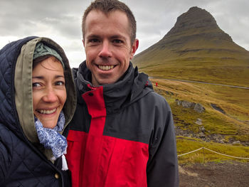 Portrait of smiling couple standing against mountain during winter