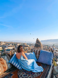 Rear view of woman sitting on terrace against sky