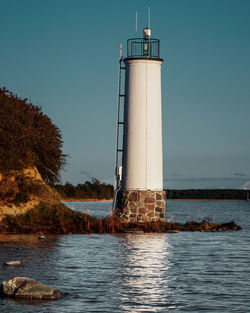 Lighthouse by lake against clear sky