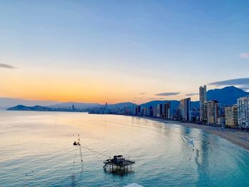 Scenic view of sea and buildings against sky during sunset
