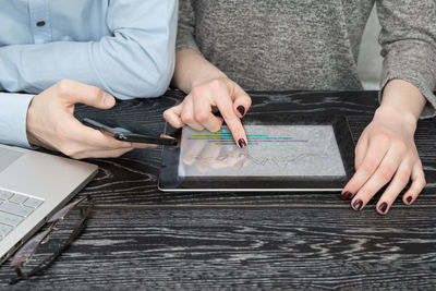 Midsection of man using mobile phone on table