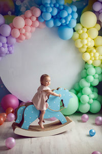 Baby girl in a pink dress is playing with a horse toy