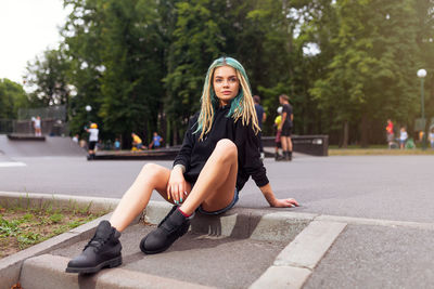 Young woman sitting on footpath