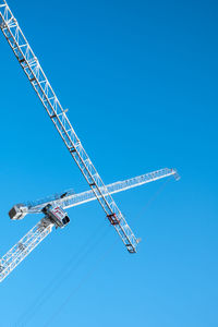 Low angle view of crane against clear blue sky