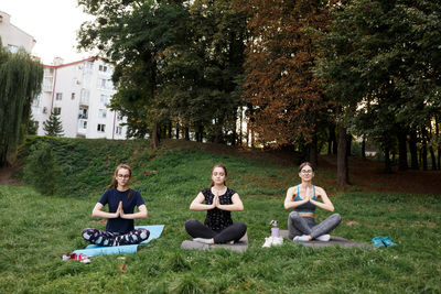 The relaxed girls is doing yoga in the park on carpet