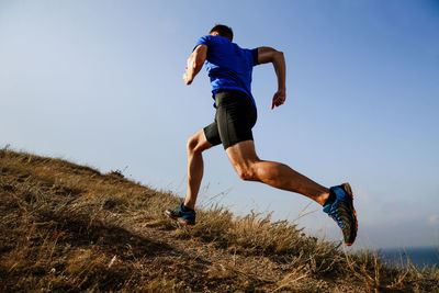 Full length of man running on hill against sky