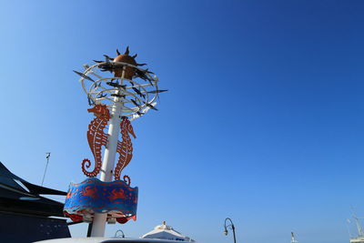 Low angle view of decoration hanging against clear blue sky