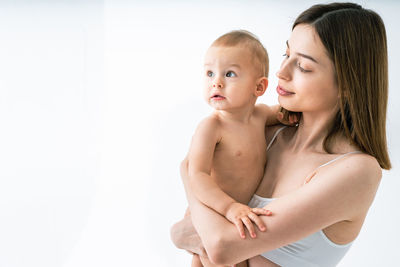 Close-up portrait of shirtless young woman against white background