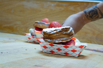Close-up of hand holding ice cream on table
