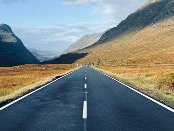 Empty road amidst mountains against sky