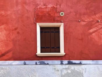 Window amidst red wall