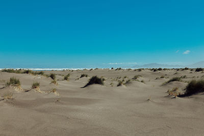 Scenic view of desert against clear blue sky