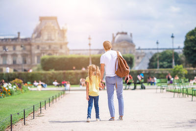 Rear view of father and daughter standing on walkway