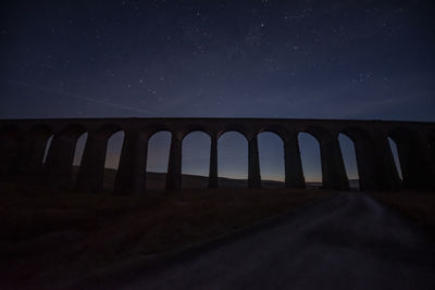 Low angle view of arch bridge against sky at night