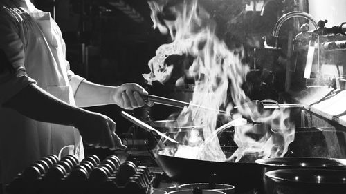 Chef stir fry busy cooking in kitchen. chef stir fry the food in a frying pan, smoke and splatter 