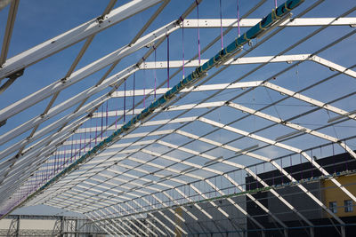 Metallic ceiling structure under construction and blue sky in background.