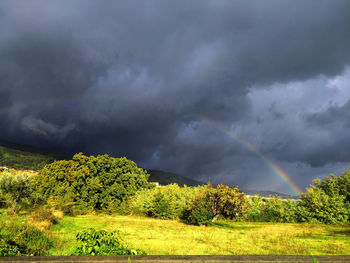 Scenic view of rainbow over landscape against cloudy sky