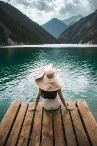 Rear view of woman looking at lake against mountain range