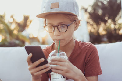 Boy using phone while having coffee outdoors