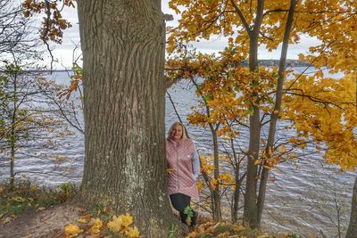 Woman standing by trees in forest during autumn