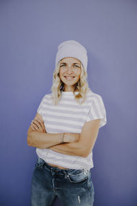 Portrait of young woman holding gift against blue background