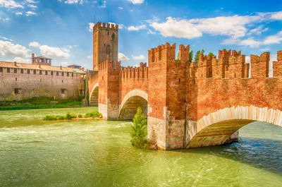 Arch bridge over river against buildings