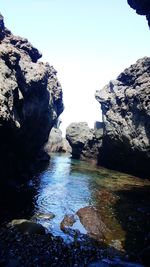 Rocks in sea against clear sky