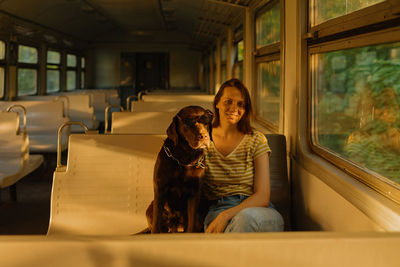 Woman and retriever dog ride a train, look out the window. traveling with a pet on public transport