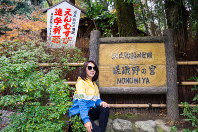 Full length of young woman with text sign on tree