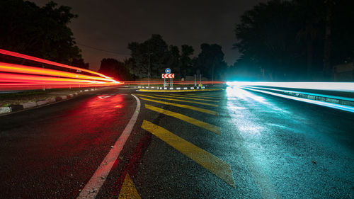 Light trails on road against sky at night