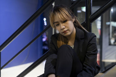 Close-up of thoughtful businesswoman sitting against railing