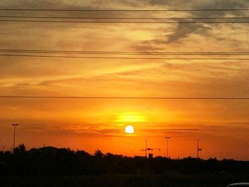 Silhouette of power lines against sunset sky