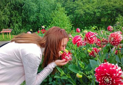 Rear view of smiling young woman with flowers in yard