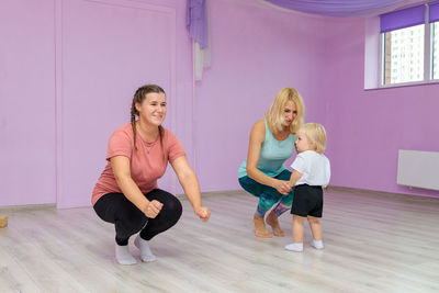 Mom and baby are doing exercises with an instructor in the gym.