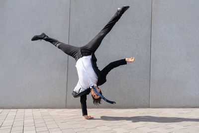 Low section of woman jumping against wall