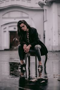 Portrait of young woman sitting in rain