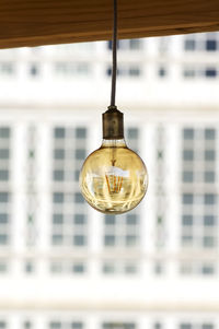 Low angle view of light bulb hanging on ceiling in building