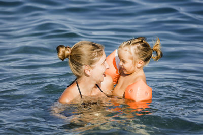 Smiling mother with daughter swimming in sea