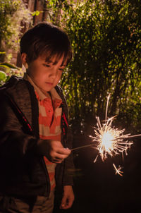 Boy holding umbrella while standing at night