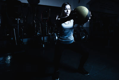 Full length of young woman exercising at gym