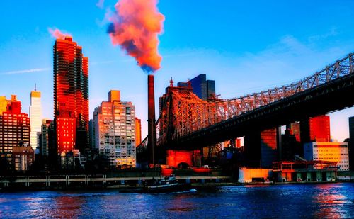 Bridge over river by buildings against sky in city