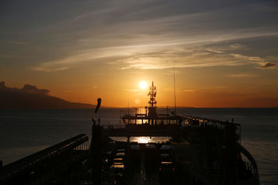 Silhouette pier over sea against sky during sunset