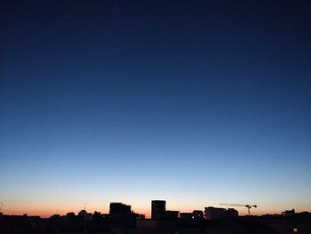 Silhouette buildings against clear sky at sunset