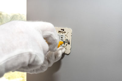 Close-up of hand holding camera against wall at home