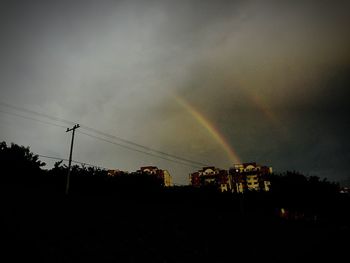 Low angle view of rainbow over trees against sky