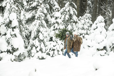 Boyfriend and girlfriend walking in forest during winter