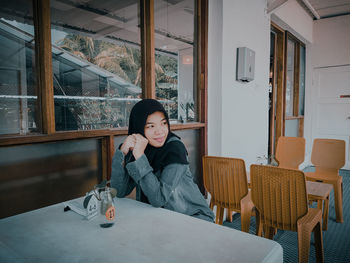 Smiling young woman looking away while sitting at cafe