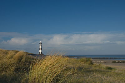 Lighthouse by sea against sky