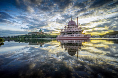 Mosque by lake during sunset