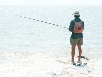 Rear view of man fishing on beach